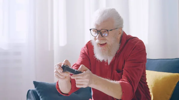 An excited mature man plays a video game, controlling the character with a joystick, demonstrating his contemporary grandpa vibe