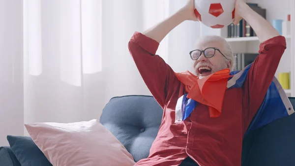An extremely excited old man celebrates the victory of his favorite French football team