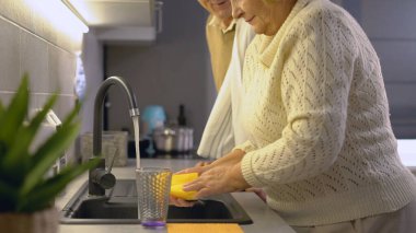 Aile yemeğinden sonra bulaşıkları yıkarken gülümseyen bir adam ve kadın.