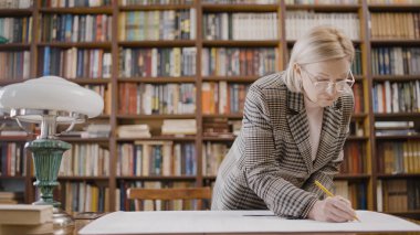 Bir bina planı yapan, plan çizen, ölçüm yapan bir kadın mimar.