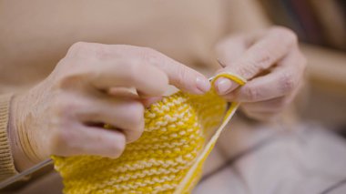 Emeklilikten sonra evde örgü ören son sınıf bir kadının ellerine yakın çekim.