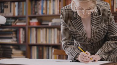 Üst düzey kadın ev projesinin planlarını çiziyor, mimarlık okuyor.