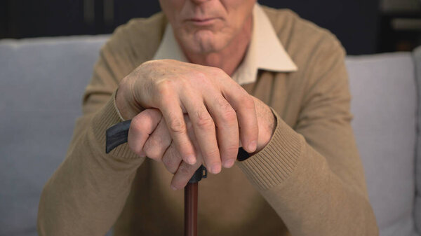 An old male putting together his hands, aging diseases and the importance of elderly health care in a nursing home