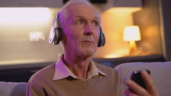A retired man in headphones is listening to the radio, indulging in his hobby and entertainment