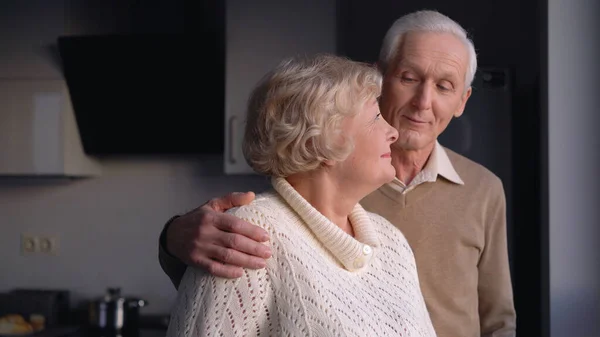 一个年长的男人拥抱他的妻子 长期的婚姻中的爱和关心 家庭的价值观 图库图片