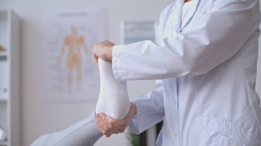 Bir travmatolog, bir spor sakatlığından sonra rehabilitasyona odaklanarak hastanın ayak egzersizini kolaylaştırır.