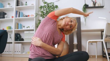 Bir kadın fitness eğitmeni çevrimiçi bir eğitim sırasında yerde egzersiz yapar.