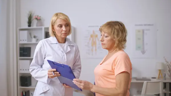 A rehabilitation clinic doctor discusses a treatment plan with a senior patient