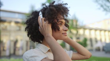 Kendine güvenen genç bir kadın kulaklık takıyor ve yürüyüşe çıkıyor, özgürlük.