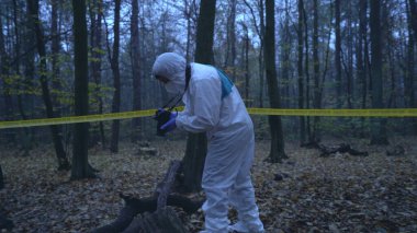 Adli tıp uzmanı olay yerinde bir kadın cesediyle birlikte kanıtları fotoğraflıyor.