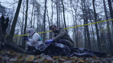 Polis memuru, kurbanın cesedini incelemek için olay yerine gelir.