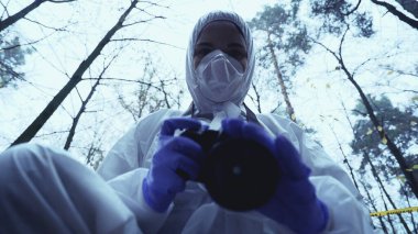 Güvenlik üniformalı müfettiş kurbanın ceset torbasının altında fotoğraflarını çekiyor.