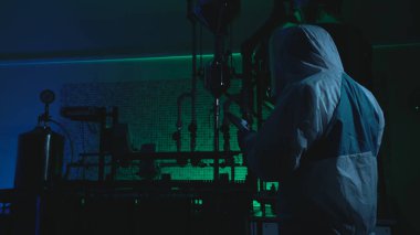 Endüstriyel casusluk yaparken koruyucu üniformalı bir adam laboratuardan gizli bilgileri çalıyor.