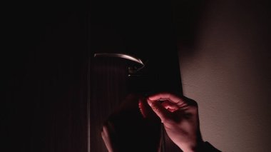 Bir adamın elleri gizlice kilidi açar ve karanlıkta bir kapıyı açar. Hırsızlık suçu işler.