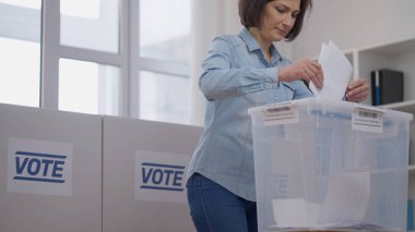 Kadın oy kullanma merkezinde oy veriyor ve sandığa oy atıyor, seçim günü, demokrasi