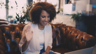 Videoda gülümseyen Afrikalı kadın, sanal toplantı sırasında kameraya el sallıyor.