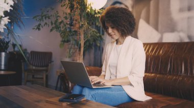 Samimi bir kafede, laptopta uzaktan çalışan kararlı bir kadın.