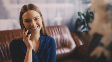 Genç bir kadın rahat bir yerde telefonla konuşuyor, arkadaşlarıyla bir toplantı düzenliyor.