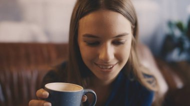 Büyüleyici kahve dükkanında porselen bardaktan kahve içen genç bir kadın.