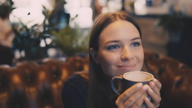 Kafede tek başına kahvesini yudumlayan rüya gibi bir kadının yakınlaşması.