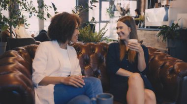 İki kadın şehir kafesinde sohbet edip kahve içiyor, modern arkadaşlık yaşam tarzı.