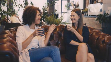 Bayan arkadaşlar kahve içip sohbet ediyorlar, keyifli dakikalar geçiriyorlar.
