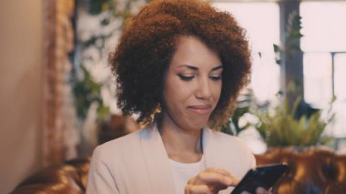 Kafede akıllı telefon kullanan Afro-Amerikan kadının yakın çekimi, Z Geni yaşam tarzı.