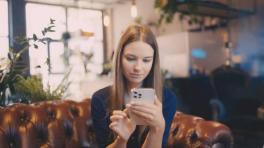 Kafe 'de dijital çağda akıllı telefondan mesajlaşan ciddi genç bir kadın.