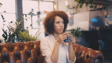 Kafede kahve içen üzgün Afrikalı Amerikalı kadın, derin düşüncelere dalmış.