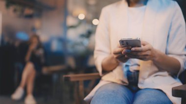 Kafede dinlenen, akıllı telefondan mesaj atan, rahat ve sakin bir kadın.