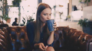 Kafeteryada sıcak kahve ve kahvaltıdan hoşlanan genç bir kadın.