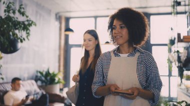 Dost canlısı siyah garson kahve dükkanındaki bayan müşteriye masayı gösteriyor.