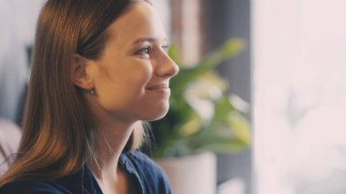 Çekici, genç bir kadın. İçtenlikle gülümsüyor, tatmin oluyor ve iyi bir ruh hali içinde.