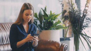 Kafede ücretsiz Wi-Fi kullanan meşgul bir kadın, akıllı telefondan çevrimiçi sipariş veriyor ve mesajlaşıyor