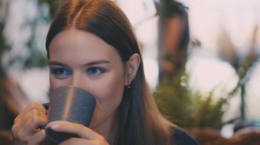 Rahat genç bayan rahat bir kafede aromatik kahvenin tadını çıkarıyor, huzurlu bir an.