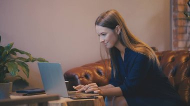 Serbest çalışan kadın dizüstü bilgisayara odaklanmış, günlük çalışma alanındaki uzak proje üzerinde çalışıyor.