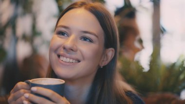Genç bir kadın yeni demlenmiş kahvenin tadını çıkarıyor. Kafede kendini sakin ve rahat hissediyor.