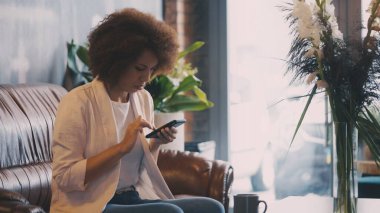 Siyahi kadın, kahve dükkanında akıllı telefon uygulamalarını kontrol ediyor, bankacılık ya da alışveriş yapıyor.