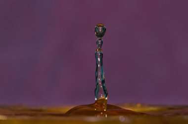 Renkli menekşe arka planda izole edilmiş su damlacığının soyut fotoğrafı. Suyla eğlenmek..