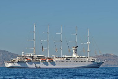 Denizdeki dev kruvazör gemisi. Mavi arkaplanda izole edilmiş, metin için boşluk. Yunanistan 'ın Santorini adalarında tatil.