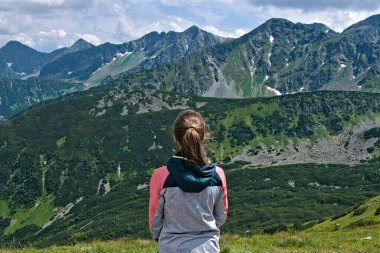 Genç kadın bankta oturmuş Zuberec kasabası yakınlarındaki Vysoke Tatry dağlarının yüksek tepelerini seyrediyor. Spalena Dolina 'daki bankta dağ gölleri ve teleferik istasyonunun yanında. Slovakya.
