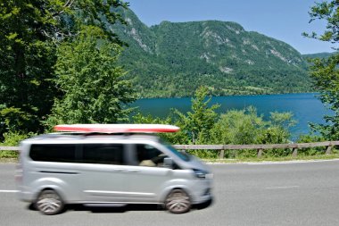 Slovenya 'daki Bohinj Gölü' nün etrafında bir karavan otomobili. Çatıda raket var. Aile yaz tatili ve yaz su aktiviteleri. 