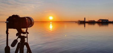 Fotoğrafçı gün batımında Neusiedler See 'deki Podo plajında ünlü deniz fenerinin fotoğrafını çekiyor. Podersdorf am See 'nin turistik cazibesi. Burgenland, Avusturya.