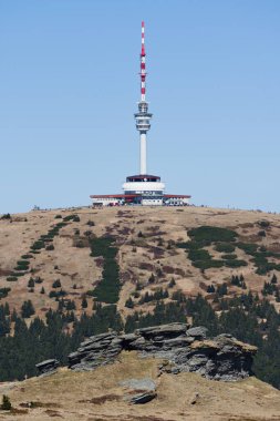 Mala Moravka, Çek Cumhuriyeti - 20 Nisan 2025: Övülen dağın tepesindeki televizyon vericisi ve gözlem kulesi ve Petrovy kameny adlı kayalar. 