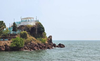 A rocky outcrop overlooking the sea with a small pavilion on top. the Dona Paula viewpoint clipart