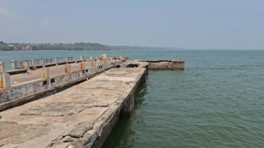 Dona Paula 'nın bakış açısına göre suya uzanan beton iskele muhtemelen eski ya da işlevsel bir rıhtımın parçası. Denizin engin genişliği ve uzak yeşillikleriyle ortam sakin görünüyor..