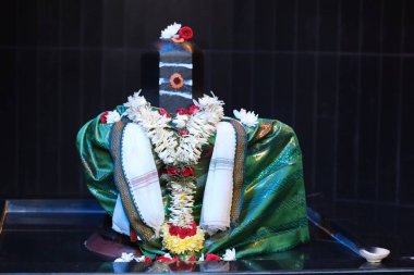 Şiv Ling 'i süsleyen geleneksel bir Shiva Lingam çiçek, çelenk ve yeşil ipek kumaşla süslenmiş ayinler ve dualar sırasında, Hindu kültüründe bağlılık ve maneviyatı sembolize eder..