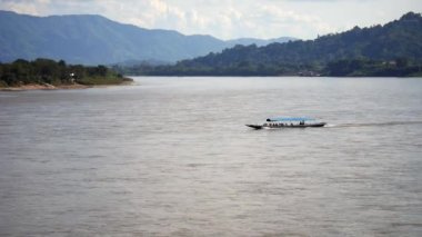 Mekong Nehri boyunca seyreden yavaş bir tekne, Mekong Nehri 'nden hareket eden yerel bir tekne Tayland ve Laos sınırı arasında, nehirde tekne nakliyesi, nakliye gemisi...