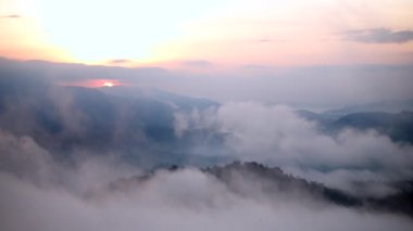 Sis dağların içinden akar, güneş tropikal ormanlara doğru parıldar, sisler sabah dağların tepelerinde sürüklenir, dağın tepesinde yavaşça süzülen sis örtüsü
