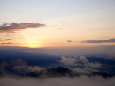 Sis dağların içinden akar, güneş tropikal ormanlara doğru parıldar, sisler sabah dağların tepelerinde sürüklenir, dağın tepesinde yavaşça süzülen sis örtüsü